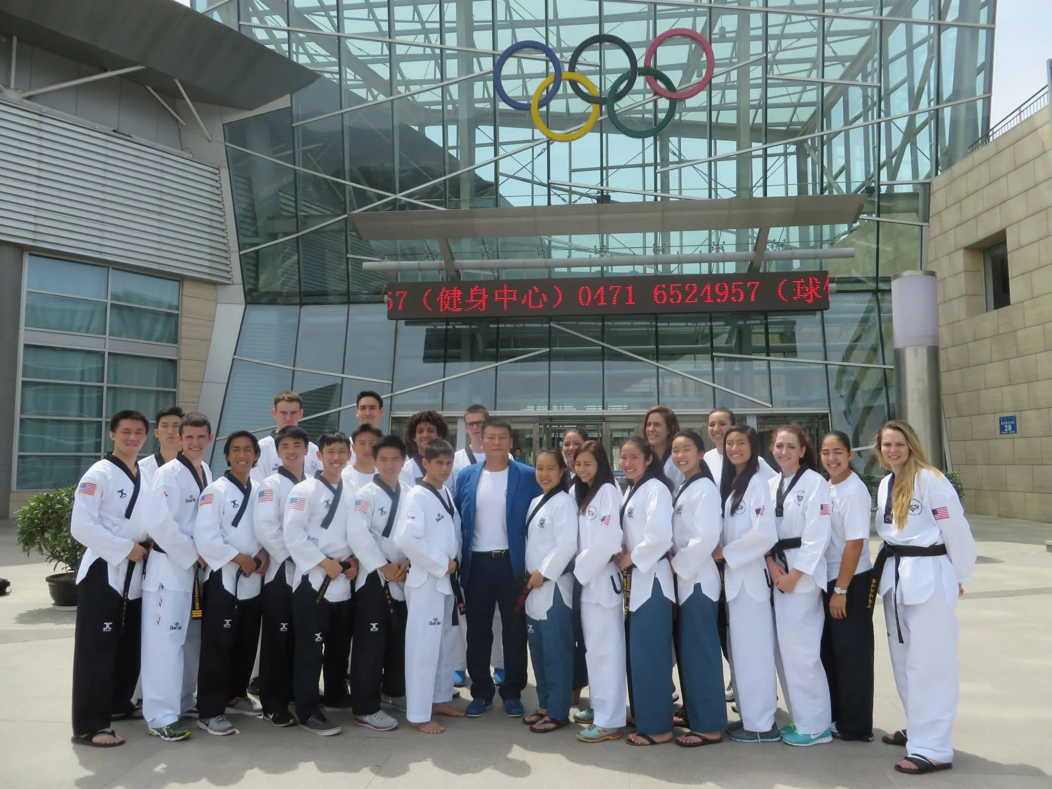 A team of Taekwondo athletes in uniform outside an Olympic training center